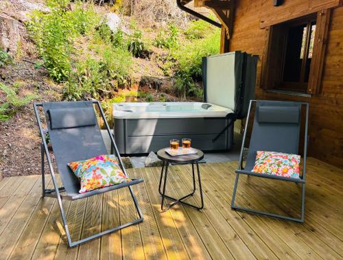 two chairs and a table on a deck with a tub at Chalet Les Cimes - Sauna - Jacuzzi in Gérardmer