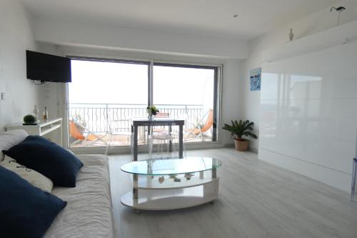 un salon avec un canapé et une table en verre dans l'établissement Ocean vert - front de mer - balcon, à La Baule