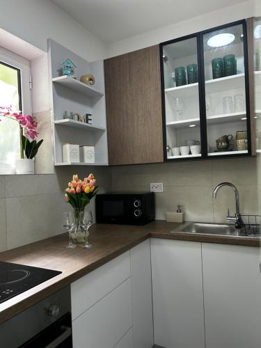 a kitchen with white cabinets and flowers in a vase at Fisherman's House Gušti in Kamenari