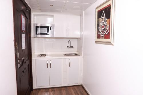 Una cocina blanca con fregadero y microondas. en فندق ابرال الفندقية, en Medina