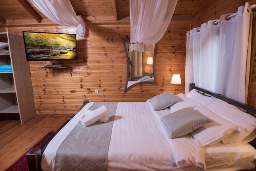 a bedroom with a large bed in a wooden room at כחול ירוק בכפר - בקתות מהממות עם ג'קוזי ובריכה מחוממת in Had Nes