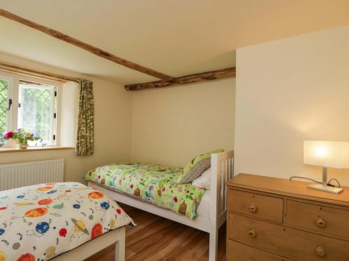 a bedroom with two beds and a dresser at Keepers Cottage in Devizes
