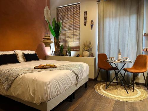 a bedroom with a bed and a table and chairs at Le Jacaranda - Suite africaine - Sauna & Netflix in Sérignan