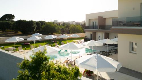 a pool with white umbrellas and tables and chairs at Eleia Domos in Monopoli