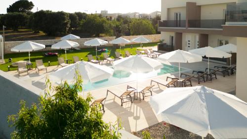 an outdoor pool with tables and chairs and umbrellas at Eleia Domos in Monopoli