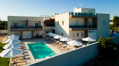 a building with a swimming pool and chairs and umbrellas at Eleia Domos in Monopoli