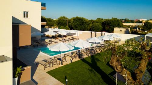 an outdoor patio with tables and white umbrellas at Eleia Domos in Monopoli
