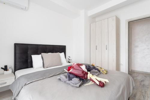 a white bedroom with a large bed with a black headboard at Vision apartmani Vrnjačka Banja in Vrnjačka Banja