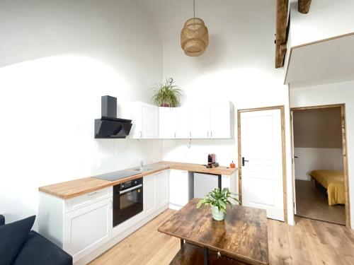 a kitchen with white cabinets and a wooden table at Domaine Poule Noire exclusif in Égreville