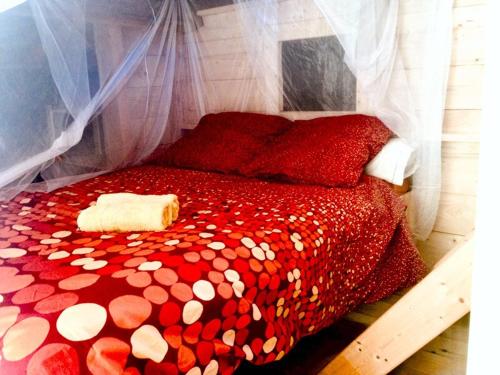 - une couette rouge sur un lit dans l'établissement La cabane des Raspes, à Montjaux