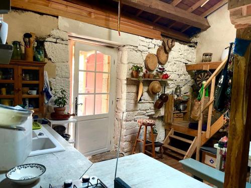 une cuisine avec un mur en pierre et une fenêtre dans l'établissement La cabane des Raspes, à Montjaux