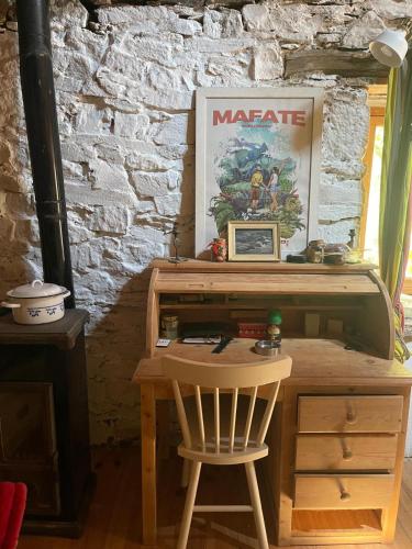 - un bureau en bois avec une chaise à côté d'un mur en briques dans l'établissement La cabane des Raspes, à Montjaux
