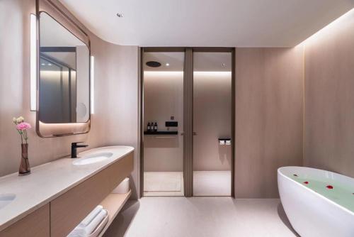 a bathroom with a tub and a toilet and a sink at 烟台滨海广场桔子水晶酒店 in Yantai