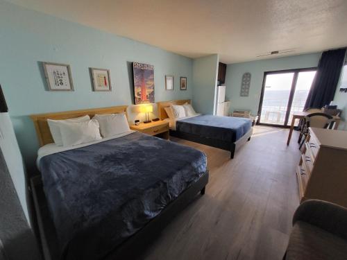 a hotel room with two beds and a couch at Beachside Hotel - POOL IS OPEN! in Daytona Beach