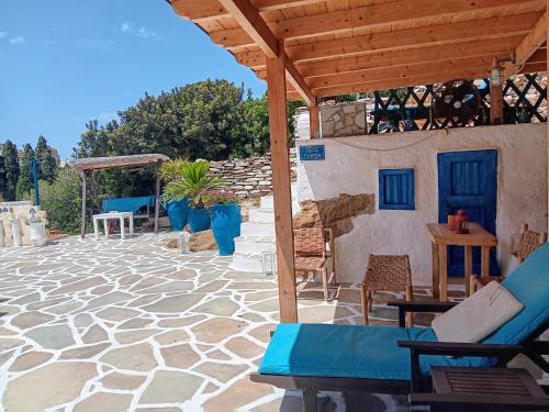 a stone patio with chairs and a wooden pergola at Villa Rena in Batsi