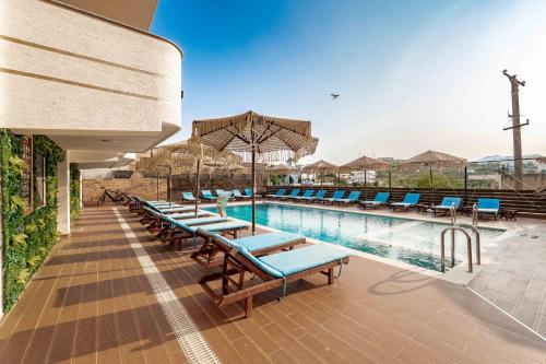 a swimming pool with lounge chairs and an umbrella at Vila Shpetimi in Ksamil