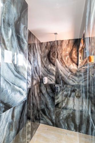 a bathroom with a shower with a marble wall at Vila Shpetimi in Ksamil