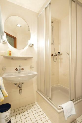 a white bathroom with a shower and a sink at Hotel Deutsches Haus in Kurort Gohrisch