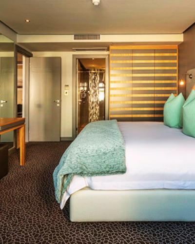 a bedroom with a bed and a desk in a room at Krystal Beach Hotel in Gordonʼs Bay