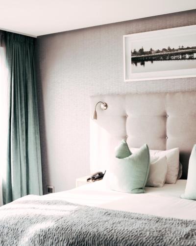 a bedroom with a white bed with a green curtain at Krystal Beach Hotel in Gordonʼs Bay