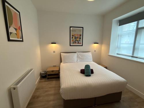 a bedroom with a white bed with a green item on it at Luxury 3 bedroom 2 bathroom All ground floor centrally located - 2 Queen Street - Ashbrook Serviced Apartments in Abingdon