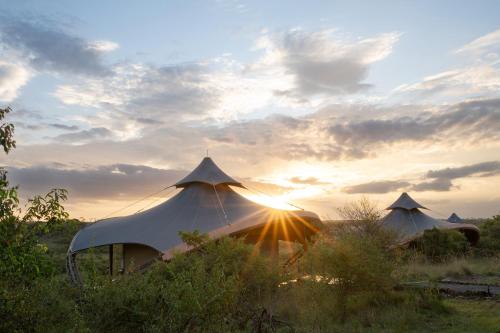 two white tents in a field with the sunset at Mahali Mzuri in Aitong