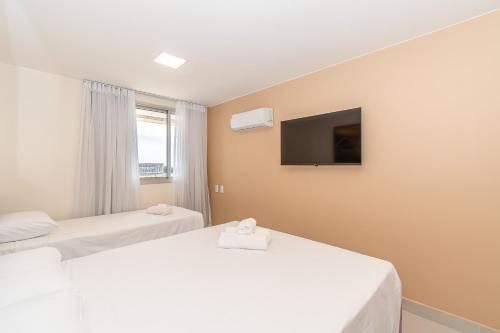 two beds in a room with a tv on the wall at BSB STAY Torre Flats Particulares - Mercure Líder in Brasilia