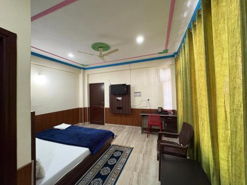 ダラムシャーラーにあるYes Comfort Villa Guest Houseのベッド、デスク、キッチンが備わる客室です。