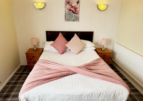 a bedroom with a large bed with pink and white sheets at The Oakland Hotel in Woodham Ferrers