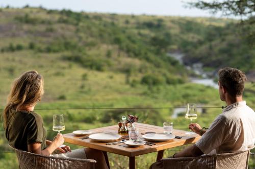 a man and woman sitting at a table with wine glasses at Mahali Mzuri in Aitong