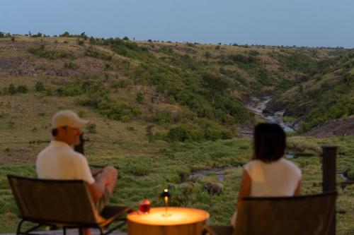 a man and a woman sitting in chairs watching elephants at Mahali Mzuri in Aitong