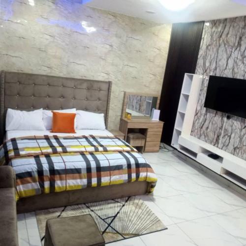 a bedroom with a bed and a flat screen tv at Spring Garden Lekki Phase 2 in Ibeju