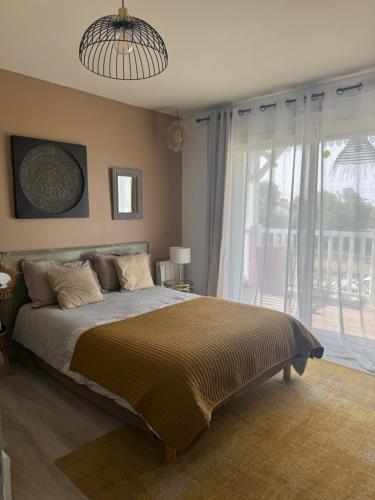 une chambre avec un lit et une grande fenêtre dans l'établissement Villa carioca, à Gujan-Mestras