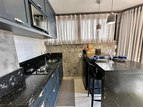 a kitchen with black counter tops and blue cabinets at Loft para Casal em Bombinhas - Sem Garagem in Bombinhas