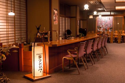 a bar with a row of chairs lined up at a bar at かっぱの宿旅館三治郎 in Zao