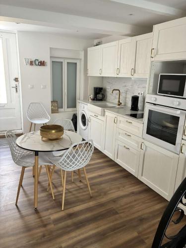 une cuisine avec des armoires blanches et une table et des chaises dans l'établissement Solea, à Lézignan-Corbières