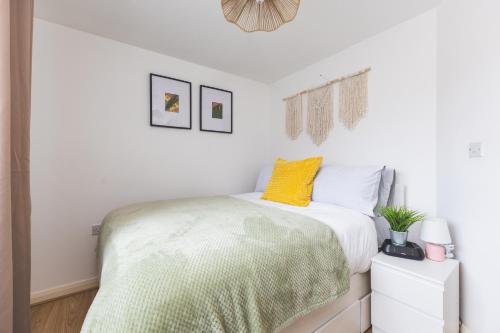 a bedroom with a bed with a yellow pillow on it at Spacious Wembley Flat Comfy Beds 2 Baths in London