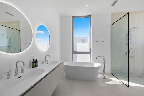 a white bathroom with a tub and a shower at South Bank in Long Bay Hills