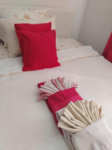 a white bed with red pillows and towels on it at Apartman Mira in Požarevac