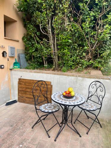 a table and two chairs with a bowl of fruit on it at B&B il Castelletto Siena in Montaperti
