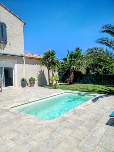 une piscine devant une maison avec des palmiers dans l'établissement Cigales, à Belcodène
