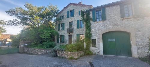 a large brick house with a green garage at Mas Montluzia in Cascastel-des-Corbières