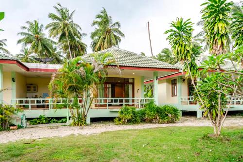 ein Haus mit Palmen davor in der Unterkunft Green Heaven Bungalows in Nathon Bay