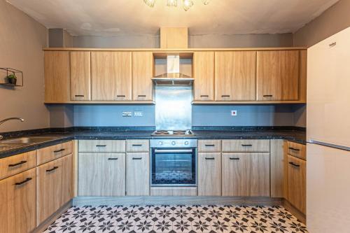 a kitchen with wooden cabinets and a stove at Parkside Mayfair Apartment in Wakefield