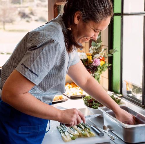 a woman preparing vegetables on a cutting board at Kau Yatún Hotel Boutique in El Calafate
