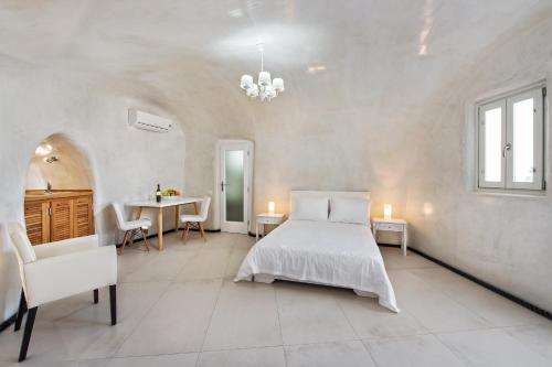 a white bedroom with a bed and a table at Spilies by Thireas in Vourvoúlos
