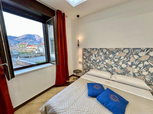 a bedroom with a bed with blue pillows and a window at La Maison Du Soleil Rooms in Agerola