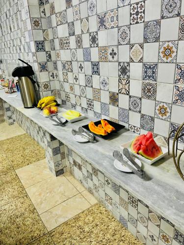 a table with plates of food on a tile wall at Hotel Nacional in Sobral