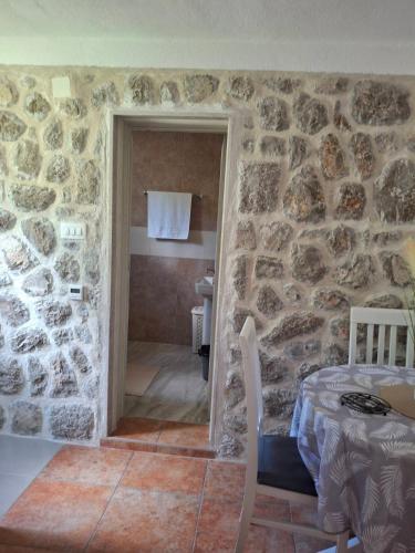 een kamer met een stenen muur met een tafel en een badkamer bij Anastasija in Merdari