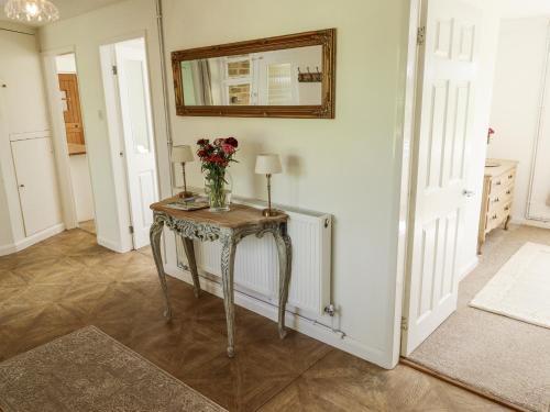 a room with a table with a vase of flowers on it at Lake View Cottage in Alford
